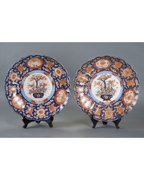 1002-Pareja platos en porcelana Japonesa. Imari. S. XIX. Decoración polícroma en tonos rojizos y azules con campo decorado con jarrón con flores. Perímetro