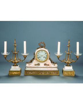 466-Reloj de sobremesa con guarnición de candelabros de dos luces en metal dorado y mármol blanco veteado. Esfera de numeración romana.  