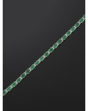 1053-CLÁSICA PULSERA RIVIERE DE ESMERALDAS Y BRILLANTES. sobre una montura de finas garras en oro blanco de 18k. Peso total de los brillantes: 0.42 ct. apr