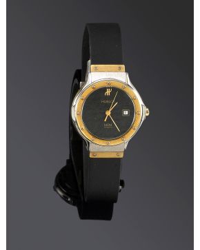 1272-HUBLOT RELOJ DE PULSERA PARA SEÑORA. CAJA EN ACERO Y BISEL EN ORO AMARILLO MATE DE 18K. MOVIMIENTO SUIZO DE CUARZO. Esfera negra con numeración a pu