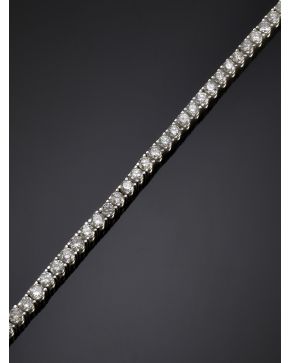 1080-CLÁSICA PULSERA RIVIERE DE BRILLANTES EN GARRAS. Montura de oro blanco de 18k. 