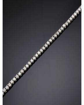 742-ELEGANTE RIVIERE DE BRILLANTES DISPUESTOS EN GARRAS. Montura de oro blanco de 18k. 