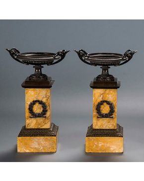 557-Decorativa pareja de copas sobre pedestal simulando mármol con corona de laurel en el fuste y aplicaciones en bronce. C. 1900.