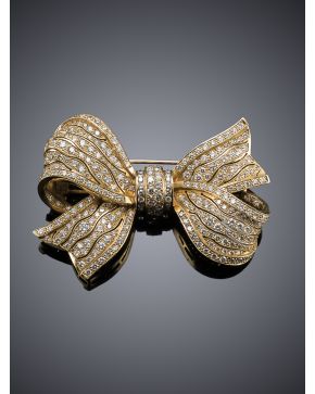 809-DELICADO BROCHE CUAJADO DE BRILLANTES EN FORMA DE LAZO. Montura de oro amarillo de 18k.