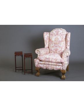 1037-Sillón orejero estilo inglés. con patas delanteras de garra sobre bola y tapicería en tela rosa con grutescos. Altura: 116 cm.