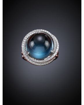 423-SORTIJA CABUJÓN DE TOPACIO AZUL DE 19.40CT.APROX Y ORLAS ENTRELAZADAS DE BRILLANTES. Montura de oro blanco de 18k. 