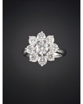 1074-ELEGANTE SORTIJA CON UN DISEÑO FLORAL EN CUYO CENTRO SE ENCUENTRA UN DIAMANTE DE 0.72 CT.APROX. ORLADO POR 8 BRILLANTES DE MENOR TAMAÑO. CALIDAD EXTRA