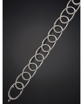 683-ELEGANTE PULSERA DE ÓVALOS ENTRELADAZOS DECORADOS EN UNO DE SUS EXTREMOS POR CHISPITAS DE BRILLANTES. Montura en oro blanco de 19k.