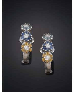 986-PENDIENTES DE TRES FLORES DECORADAS CON PÉTALOS DE TOPACIOS AZULES Y AMARILLOS Y ZAFIROS AZULES. Montura en oro blanco de 19k.