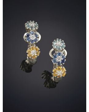 765-PENDIENTES DE TRES FLORES DECORADAS CON PÉTALOS DE TOPACIOS AZULES Y AMARILLOS Y ZAFIROS AZULES. Montura en oro blanco de 19k.