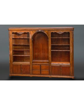 984-Elegante librería en madera con hornacina central. baldas laterales y compartimentos inferiores. Decoraciópn tallada de elementos vegetales y rocallas