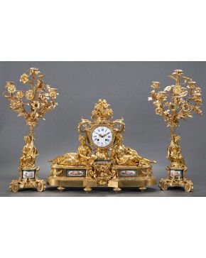 1049-Importante guarnición Napoleón III. Francia. s. XIX. En bronce dorado con placas en porcelana de Sèvres. Formada por reloj de sobremesa y candelabros 