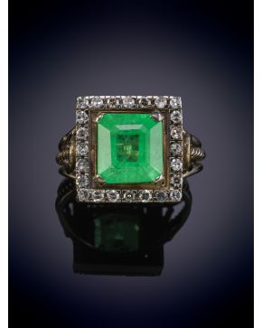 215-SORTIJA CON UNA ESMERALDA CENTRAL DE 5,80CT. APROX. DE INTENSO COLOR VERDE ORLADA POR BRILLANTES sobre una montura de oro blanco de 18k. 