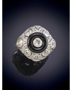 242-ELEGANTE SORTIJA ESTILO OJO DE PERDIZ CON UN DIAMANTE CENTRAL ORLADO POR ONIX sobre una montura en oro blanco de 18K.