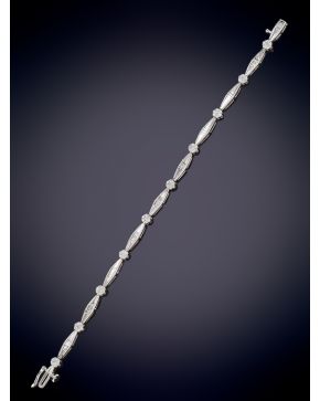 347-ELEGANTE PULSERA DE DIAMANTES TALLA BAGUETTE Y BRILLANTES EN FORMA DE ROSETÓN  ARTICULADA sobre una montura en oro blanco de 18K.