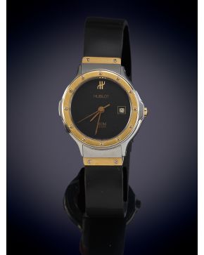 776-HUBLOT RELOJ DE PULSERA PARA SEÑORA. CAJA EN ACERP Y BISEL EN ORO AMARILLO DE 18K. MOVIMIENTO SUIZO DE CUARZO. Esfera negra con numeración a trazos aplicados en el bisel. Pulsera de caucho con heb