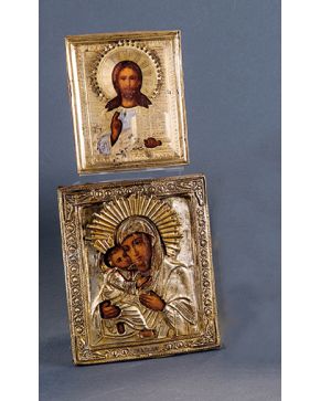 2516-Lote formado por dos iconos rusos pintandos al temple sobre tabla, S. XIX. Uno de ellos representa a Cristo bendiciendo y el otro a una Virgen con Niño. Ambos combinan caras y manos pintadas con gran detalle y un bello trabajo en plata repujada 