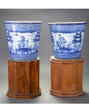 555-Pareja de maceteros en cerámica de Talavera-Ruiz de Luna, c. 1900, Con decoración en azul y blanco de arquitecturas y animales en paisajes. Con marcas. Uno de ellos con desperfectos. Sobre peanas octogonales en madera con tapas en cerámica de cue