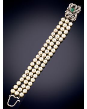 264-PULSERA DE TRES HILOS DE PERLAS CULTIVADAS CON UN BROCHE CON ESMERALDA CENTRAL Y BRILLANTES en oro blanco de 18K.