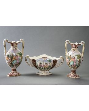 2120-Grupo en porcelana de Capodimonte formado por pareja de jarrones y centro con asas. Decoración de escenas mitológicas. Con marcas. Altura mayor: 39 cm.