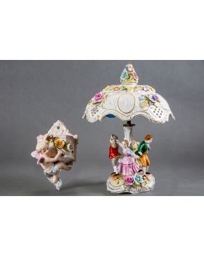 2102-Lote formado por lámpara y aplique-violetero en porcelana centroeuropea. Con decoración de personajes y amorcillos. Faltas en lámpara. Altura lámpara: 40 cm.