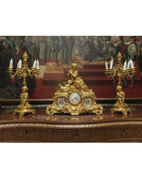 764-Guarnición compuesta por reloj de sobremesa en bronce dorado y placas de porcelana de Sévres, y candelabros de seis luces a  juego, estilo Luis XV, Francia, s. XIX.  Reloj rematado por figura f