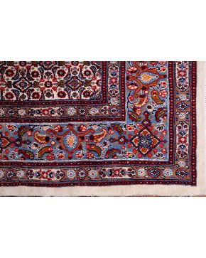 631-Alfombra persa en lana con abigarrada decoración de flores sobre campo color marfil. Cenefas en azul y rojo.  Medidas: 240x311 cm.