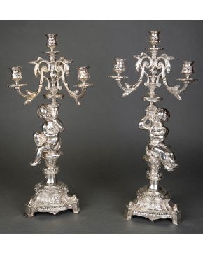 1087-Pareja de candelabros italianos de cuatro luces en plateado. C. 1900. Con figuras de querubines en el fuste y decoración vegetal y floral en relieve.  Altura: 50 cm.