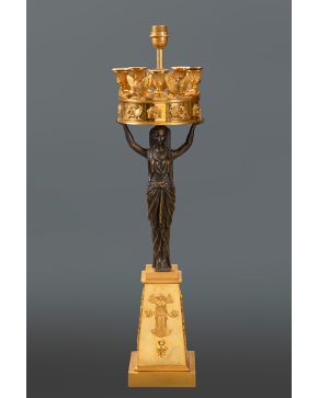 665-Gran candelabro Imperio en bronce dorado y pavonado. Rusia, s. XIX.  Fuste en forma de figura femenina egipcia portante. Decoración figurativa en relieve sobre base troncopiramidal decorada con