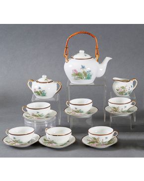 2344-Juego de té en porcelana  decorada con motivos orientales formado por tetera, lechera, azucarero y seis tazas con sus respectivos platos. Una taza con consolidación. Altura: 19 cm. 