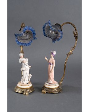 2148-Pareja de lámparas de sobremesa de estética modernista con figuras de damas en porcelana policromada y tulipas en cristal en forma de flor. Altura: 46 cm