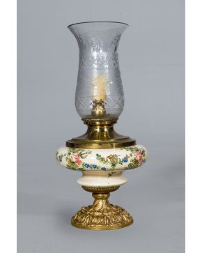 2165-Lámpara de sobremesa estilo quinqué con pie de metal dorado decoado con motivos vegetales y de tornapuntas, nudo central de porcelana con decoración de motivos vegetales y tulipa de cristal. A