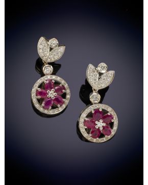 128-ELEGANTES PENDIENTES COLGANTES CON UNA FLOR DE RUBÍES ENMARCADA EN UN CÍRCULO DE BRILLANTES sobre una montura en oro blanco de 18K.