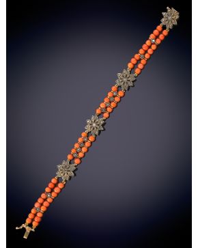 327-ELEGANTE PULSERA DE DOS HILOS DE CUENTAS DE CORAL ROJO DECORADA POR FLORES DE BRILLANTES sobre una montura en oro blanco de 14K.