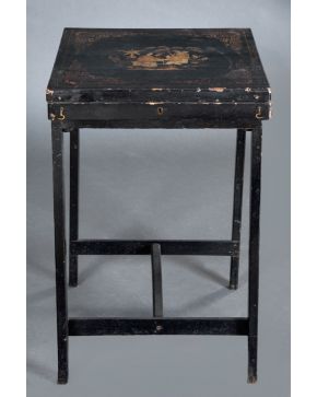 2246-Caja porta mantones en madera lacada en negro, con patas. China, s. XIX. Decorada en la tapa con detalles en dorado y escena central con personaj