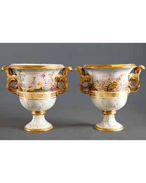 1027-Pareja de copas en porcelana esmaltada de Sèvres frisos con escenas orientales en paisaje y detalles en dorado. Asas en forma vegetal doradas.   