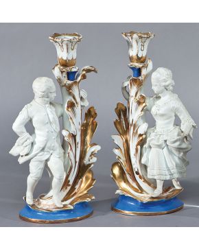 2149-Pareja de candeleros en porcelana de tipo isabelino. Uno de ellos con brazo roto. Desperfectos y faltas.Alturas: 28,5 y 34 cm