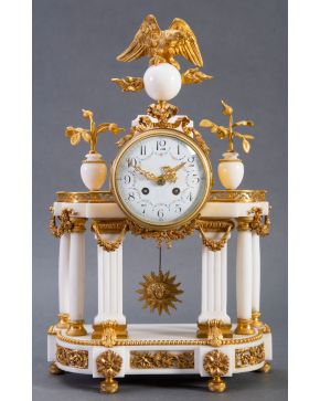 916-Reloj estilo Luis XVI en mármol blanco y bronce dorado. Gran esfera sobre columnas acanaladas y decorada por pequeños jarrones con flore