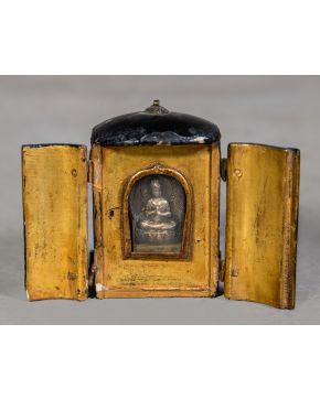 477-Pequeña capilla antigua en madera lacada en negro por fuera y dorada por dentro que cobija una pequeña figura de Buda en metal plateado.