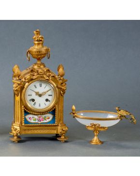 653-Lote formado por reloj de sobremesa en bronce dorado estilo Luis XVI, s. XIX, con placas en porcelana esmaltada, remate de copa y esfera con numer