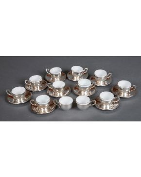 621-Juego de doce tacitas de café con sus platitos, en plata española punzonada, con marcas de Dionisio García. Pocillos en porcelana blanca.  Medidas