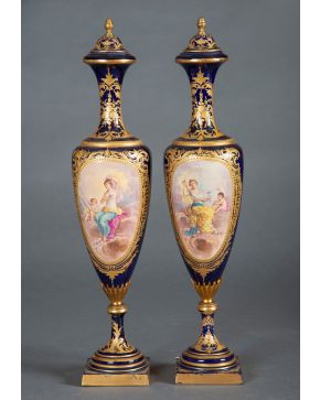 614-Pareja de jarrones con tapa en porcelana de estilo Sévres azul cobalto, c. 1890, con detalles en dorado y decoración esmaltada en reserva represen