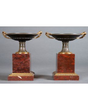 511-Pareja de copas francesas, s. XIX, en bronce pavonado con aplicaciones en bronce dorado sobre peana en mármol rojo veteado. Altura: 26 cm.