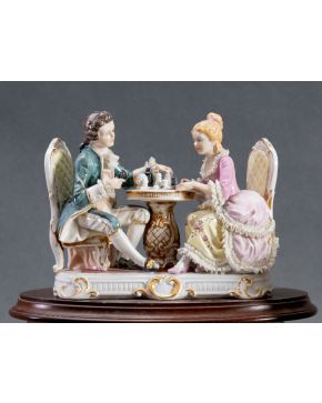 2190-Figura en porcelana centroeuropea esmaltada y policromada con pareja de cortesanos jugando al ajedrez.  Medidas: