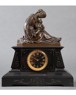 2069-Reloj de sobremesa estilo Imperio, Francia s. XIX, con representación escultórica de la Maternidad en bronce pavonado sobre p