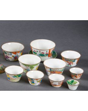 2129-Conjunto de diez vasos de diferentes tamaños en porcelana china y un plato. Decoración esmaltada con escenas palaciegas. Con