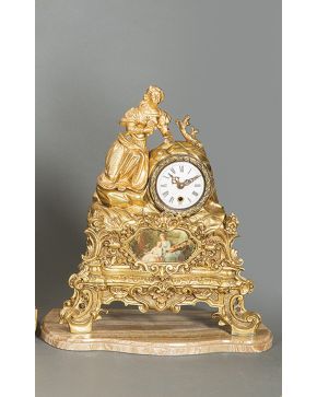 2385-Reloj de sobremesa con figura de dama en bronce dorado con decoración de rocallas y placas de esmalte con escenas festivas sobre base d