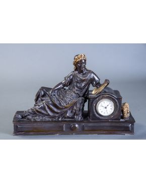 2375-Reloj de sobremesa de estilo Imperio en bronce pavonado. Apoya en la esfera con numeración romana una figura laureada de Musa que su