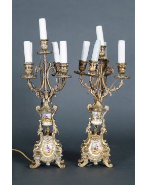 2318-Pareja de candelabros de cinco luces, ff. s. XIX. En bronce dorado, con porcelana esmaltada y policromada representando escenas pastori