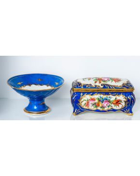 2307-Conjunto en porcelana estilo Sèvres compuesto por frutero y caja rectangular, fondo azul cobalto y flores pintadas.  Altura mayor: 16 c